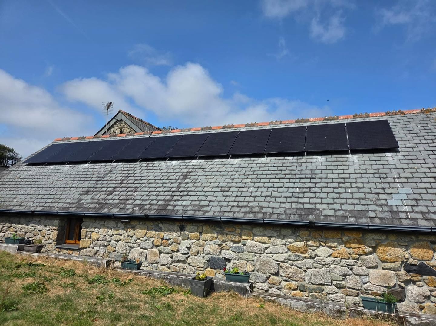 Solar panels installed on a stone barn roof at a commercial site in Roche, Cornwall